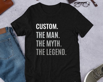 May include: Black t-shirt with white text that reads "CUSTOM. THE MAN. THE MYTH. THE LEGEND."