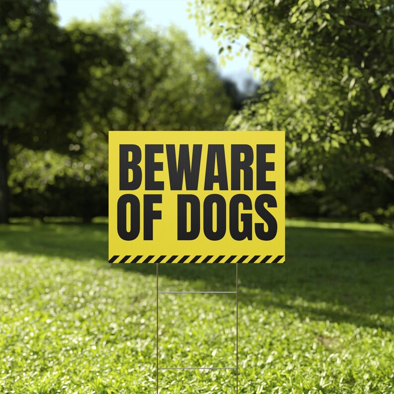 a beware of dogs sign in the grass