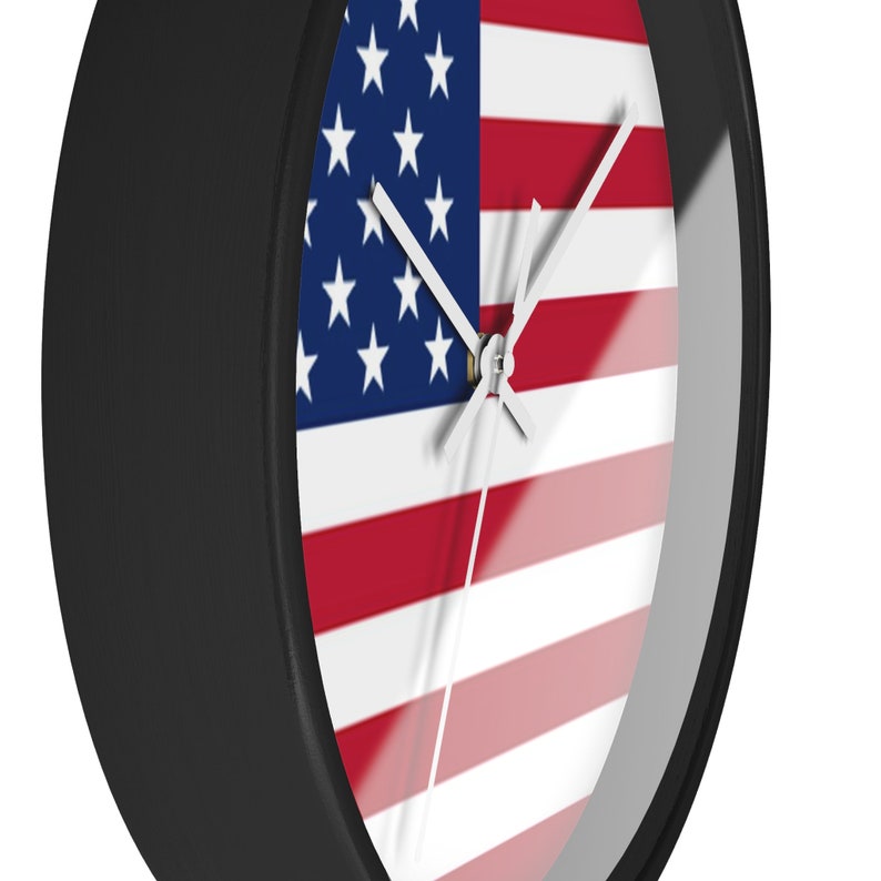 May include: A black wall clock with a clear face featuring the American flag. The clock hands are white.