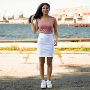 a woman in a pink top and white skirt