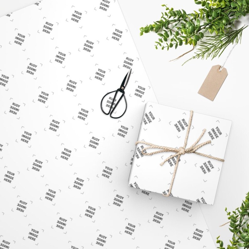 a gift wrapped in white paper with a pair of scissors on top of it