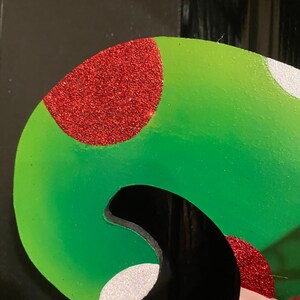 K&ouml;nnte beinhalten: Ein gr&uuml;ner und roter Weihnachtssocken mit wei&szlig;en Punkten. Der Socken ist aus Filz und hat eine glitzernde Oberfl&auml;che.