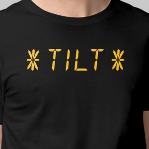 May include: Black t-shirt with the text "*TILT*" in yellow.