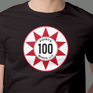 May include: Black t-shirt with a red and white circle graphic. The circle has a white starburst with the text "POINTS 100 WHEN LIT" in black.