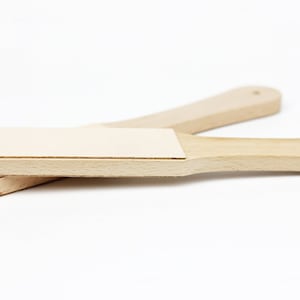 以下が含まれることがあります： 薄い茶色の仕上げが施された木製の革研磨ツール2つ。ツールは木でできており、上部に革のストリップが付いています。