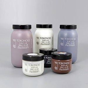 Puede incluir: Cinco botellas de acondicionador para cuero en varios tonos de marrón, blanco y morado. Las botellas están etiquetadas con "Tokonole" en caracteres japoneses e inglés. Las botellas están dispuestas en una fila sobre una superficie gris claro.