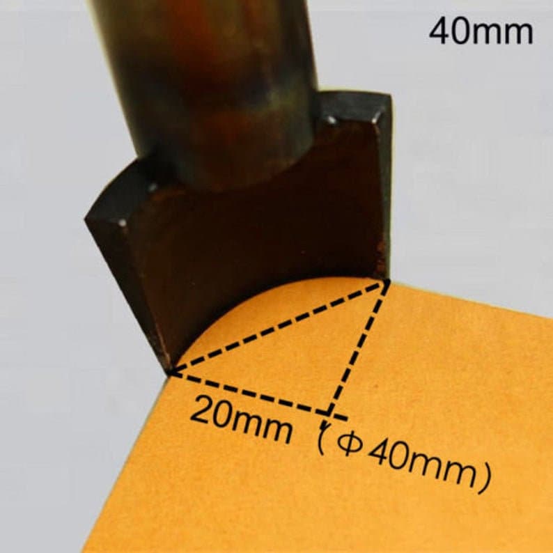 May include: A close-up of a black metal tool with a curved edge. The tool is resting on a piece of orange paper with a dashed line triangle marking a 20mm radius and a 40mm diameter.