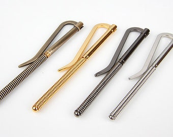 May include: Four metal money clips in different finishes: gold, silver, black, and bronze. Each clip has a spring-loaded mechanism and a curved design.
