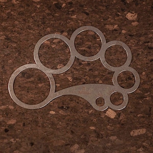 Könnte beinhalten: Ein Werkzeug aus Metall mit einer Reihe von kreisförmigen Ausschnitten in verschiedenen Größen, die mit ihren Durchmessern in Millimetern beschriftet sind. Das Werkzeug ist zum Messen der Größe von Objekten bestimmt.