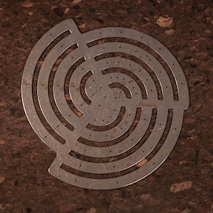 May include: A metal circle stencil with concentric circles and markings for different sizes. The stencil is marked with numbers from 12 to 48, and the word "Nautical" is printed on the stencil.