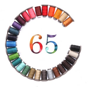 May include: A circle of 65 spools of thread in various colours, arranged in a rainbow pattern. The spools are all the same size and shape, and they are all wound with thread. The spools are arranged in a circle, with the number "65" in the centre.