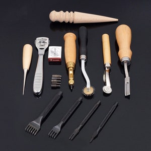 May include: A set of leather crafting tools, including a stitching awl, a stitching pony, a leather skiver, a leather punch, a stitching wheel, and a set of stitching needles. The tools are arranged on a black surface.