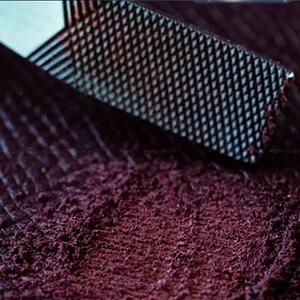 Peut inclure: Gros plan sur une poudre violette fonc&eacute;e r&acirc;p&eacute;e avec une r&acirc;pe en m&eacute;tal. La poudre est finement moulue et a une texture lisse.