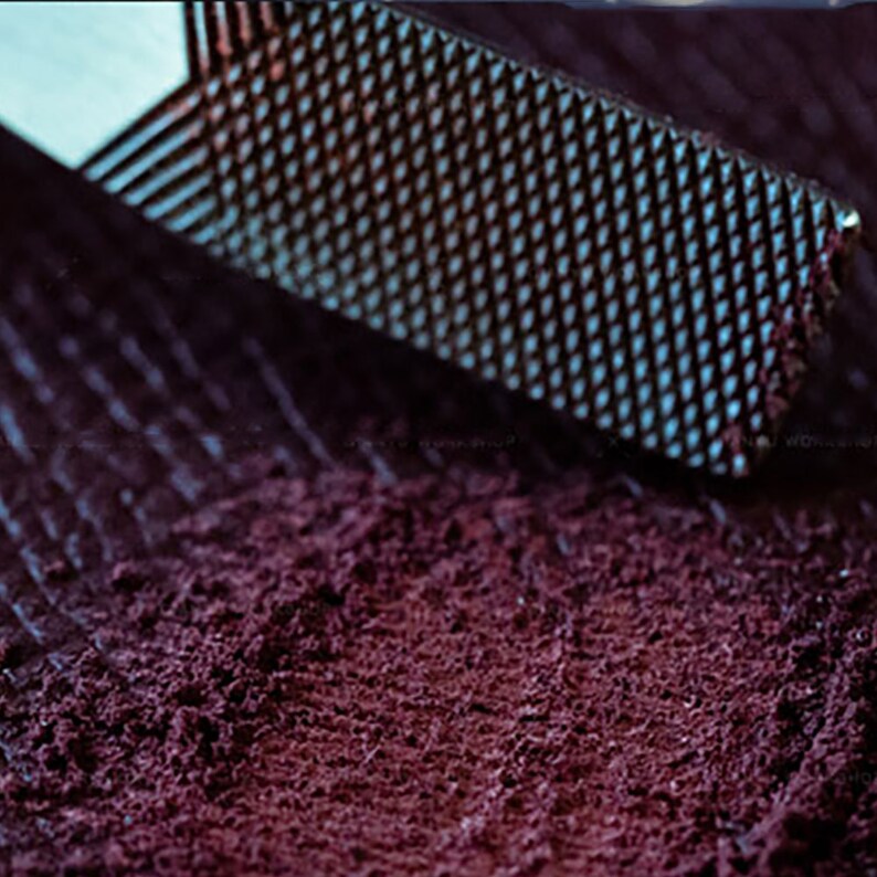Peut inclure: Gros plan sur une poudre violette fonc&eacute;e r&acirc;p&eacute;e avec une r&acirc;pe en m&eacute;tal. La poudre est finement moulue et a une texture lisse.