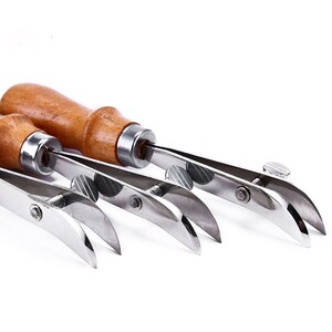 Könnte beinhalten: Drei Leder-Steppwerkzeuge mit Holzgriffen und verstellbaren Metallarmen. Die Werkzeuge werden verwendet, um gleichmäßige Stiche in Lederwaren zu erzeugen.