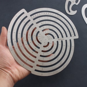 Könnte beinhalten: Ein silberner Kreis-Winkelmesser aus Metall mit einer graduierten Skala und mehreren konzentrischen Kreisen. Der Winkelmesser ist mit "Nattools" beschriftet und hat ein kleines Dreieck in der Mitte.