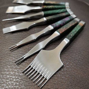 Può includere: Un set di otto strumenti per cucire il cuoio con manici in legno. Gli strumenti hanno aghi di diverse dimensioni e sono utilizzati per cucire il cuoio.