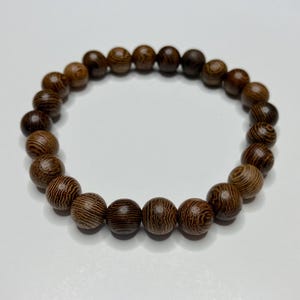 May include: A brown wooden beaded bracelet with a natural wood grain pattern.
