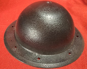 Könnte beinhalten: Ein schwarzer Helm mit einer strukturierten Oberfläche und einem breiten Rand. Der Helm hat mehrere kleine Löcher um den Rand.