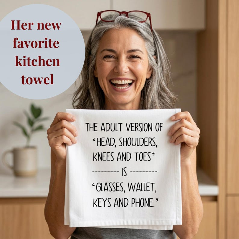 Happy older woman holding the handmade gift of a funny kitchen towel Funny Kitchen Towel Adult Humor Design Cotton Textile Dish Cloth Absorbent Material White Printed Text Joke Birthday Present Friend Housewarming Hostess Appreciation Gift Novelty Gag Item Sarcastic Comedy Perfect Kitchen Essential The Adult Version Of Head, Shoulders, Knees and Toes is Glasses, Wallet, Keys and Phone Kitchen Tea Towel Screen Printed