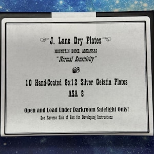 May include: A black box containing 10 hand-coated 9x12 silver gelatin plates with the text J. Lane Dry Plates, Mountain Home, Arkansas, Normal Sensitivity, ASA 8, and Open and Load Under Darkroom Safelight Only printed on the white label.