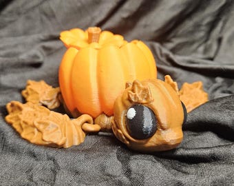May include: A 3D-printed orange pumpkin with a detailed stem and leaves, accompanied by a whimsical, cartoonish creature with a large eye. The pumpkin and creature are set against a dark, textured background, evoking a Halloween theme.