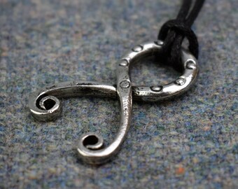 May include: A silver pendant necklace with a stylized infinity symbol design. The pendant is attached to a black cord.