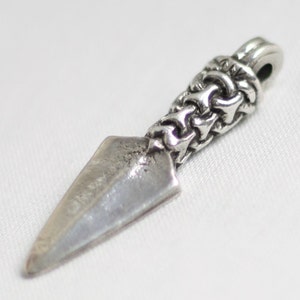 May include: Silver pendant in the shape of a spear with a detailed, intricate design on the handle.