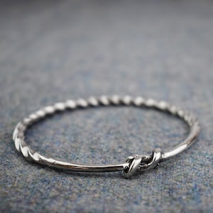 May include: A silver twisted bangle bracelet with a knot clasp.