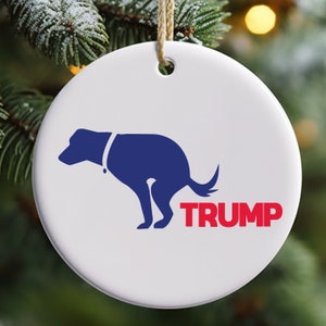May include: A white ceramic Christmas ornament with a blue silhouette of a dog defecating with the word "TRUMP" in red letters below.