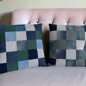 May include: Two square throw pillows with patchwork denim designs. Each pillow features a grid pattern of various denim shades, including light blue, dark blue, and green. The pillows are placed on a pink sofa.
