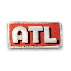 May include: A red and white embroidered patch with the text "ATL" in white letters with a black outline.