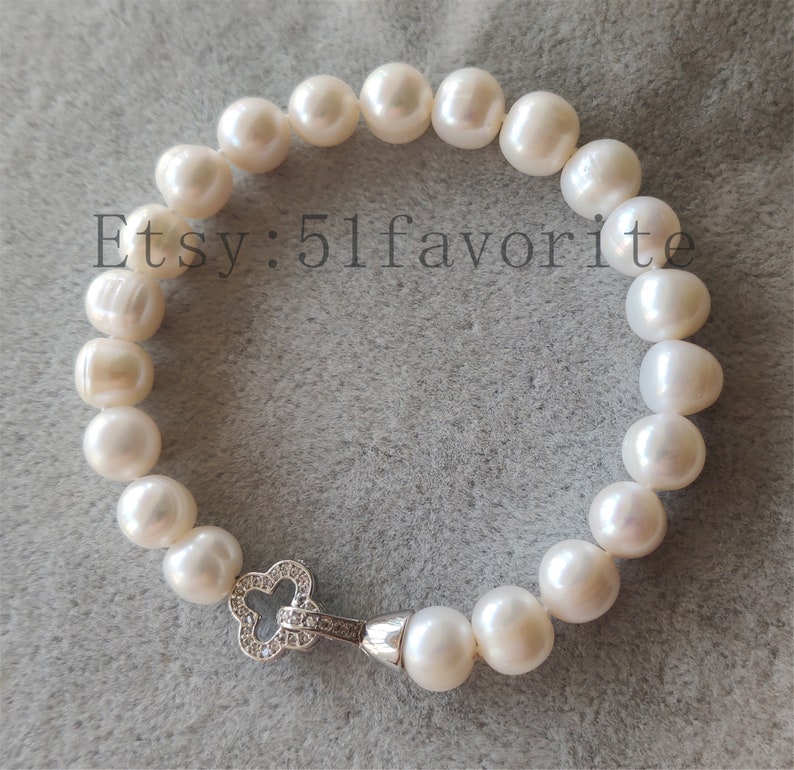 May include: A white pearl bracelet with a silver clasp. The bracelet is made of large, irregularly shaped pearls. The clasp is a clover shape with small, clear stones. The text "Etsy: 51favorite" is visible.