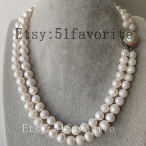 Puede incluir: Un collar de perlas de doble cadena con un cierre plateado. Las perlas son blancas y redondas.
