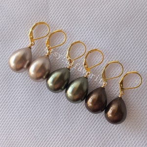 Puede incluir: Cuatro pares de pendientes de perlas en forma de lágrima con cierres de palanca dorados. Las perlas son en tonos de marrón, gris y verde.