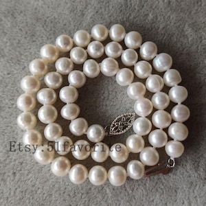 May include: A white pearl necklace with a silver clasp. The necklace is made of round pearls and is approximately 18 inches long.