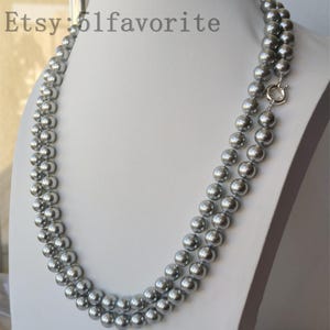 Op de afbeelding: Een dubbele ketting met grijze, bolvormige kralen. De kralen zijn aan elkaar geregen, waardoor een gelaagd effect ontstaat. Een zilverkleurige sluiting zet de ketting vast. De tekst "Etsy: 51favorite" is linksboven zichtbaar.