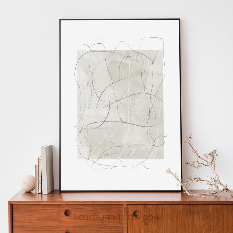 K&ouml;nnte beinhalten: Ein gerahmter abstrakter Kunstdruck mit einem hellgr&uuml;nen Aquarellhintergrund und schwarzen Linien. Der Druck befindet sich auf einem Holzregal mit einer kleinen wei&szlig;en Kugel und einem Stapel B&uuml;chern.