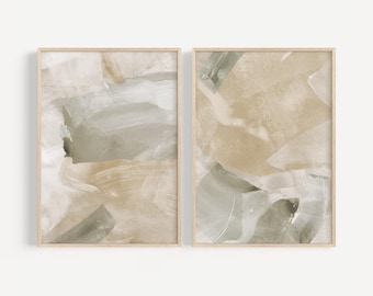 May include: Two framed abstract art prints. Each print features a blend of neutral colors, including beige, gray, and white, with brushstroke-like patterns. The artwork is encased in a light-colored wooden frame, suitable for home decor.