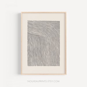 Puede incluir: Una impresión abstracta enmarcada con un diseño de líneas curvas grises y blancas. La impresión está en un marco de madera claro.