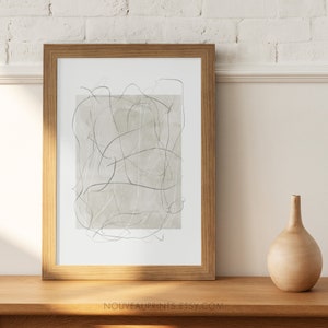K&ouml;nnte beinhalten: Ein gerahmter abstrakter Kunstdruck mit beigefarbenem Hintergrund und grauen Linien. Der Rahmen ist aus hellem Holz.