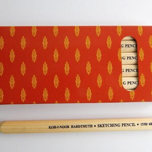 May include: A box of Koh-I-Noor Hardtmuth sketching pencils in a red and gold patterned box. The box has a window showing the pencils inside. The pencils are labelled "G PENCI". A single pencil is shown outside the box, labelled "KOH-I-NOOR HARDTMUTH SKETCHING PENCIL 1538/6B".