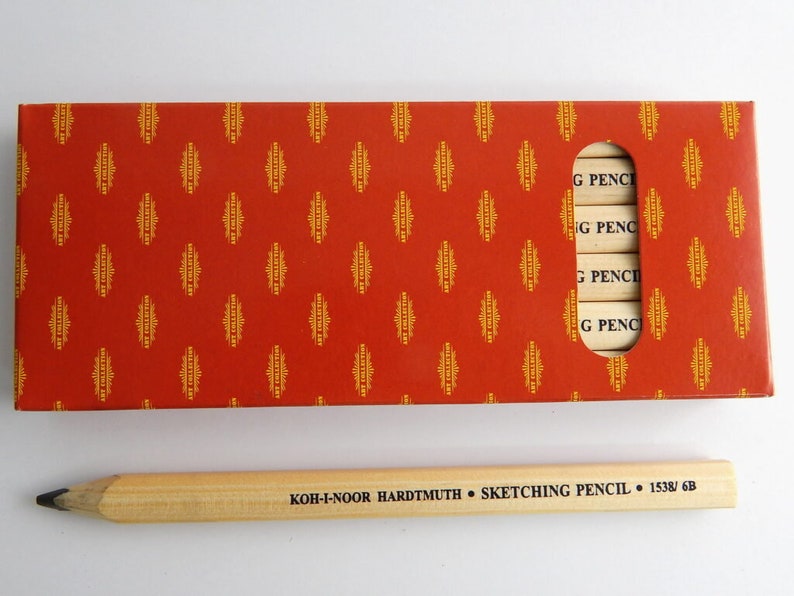 May include: A box of Koh-I-Noor Hardtmuth sketching pencils in a red and gold patterned box. The box has a window showing the pencils inside. The pencils are labelled "G PENCI". A single pencil is shown outside the box, labelled "KOH-I-NOOR HARDTMUTH SKETCHING PENCIL 1538/6B".