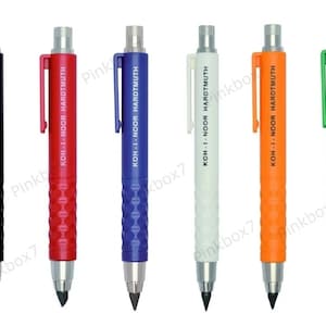 Puede incluir: Seis lápices mecánicos con cuerpos de diferentes colores: negro, rojo, azul, blanco, naranja y verde. Cada lápiz tiene el texto "KOH-I-NOOR HARDTMUTH" impreso en el lateral.