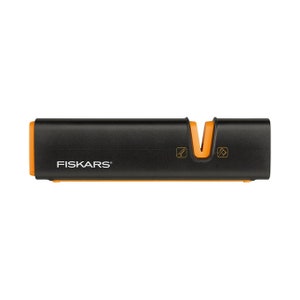 Può includere: Un affilacoltelli nero e arancione con la scritta "FISKARS" stampata sul davanti. L'affilacoltelli ha due fessure per affilare i coltelli.