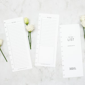 May include: Three white to-do list printable sheets with a simple design. The sheets are on a white marble background with white flowers.