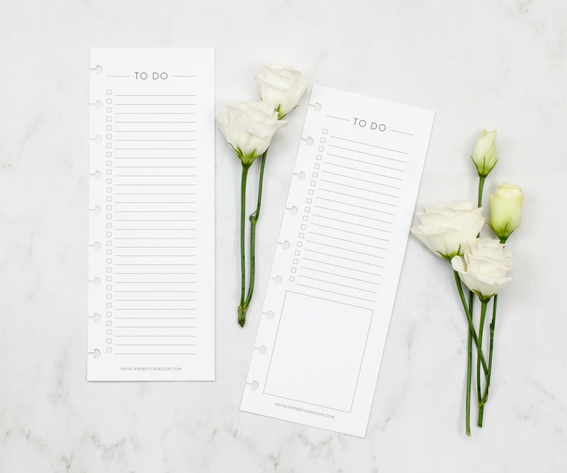 May include: Two white printable to-do list cards with a black "TO DO" title and a dotted line for checking off tasks. The cards are on a white marble surface with white flowers.