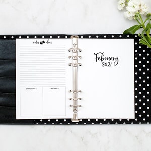 Op de afbeelding: Een zwarte en witte stippenbinder met een witte pagina open voor februari 2021. De linkerpagina heeft een sectie voor notities en idee&euml;n met gestreept papier en twee lege vakjes.