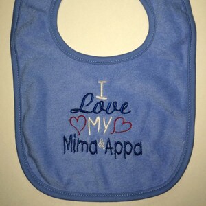 May include: A blue baby bib with white embroidery that reads "I Love My Mima & Appa" with two red hearts around the word "My".
