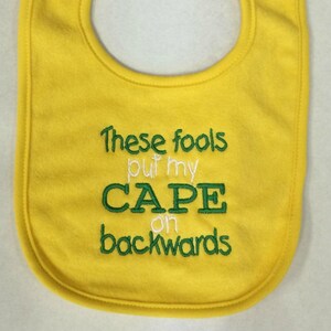 These fools put my cape on backwards embroidered bib